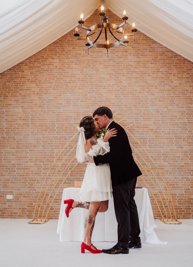 A couple kiss under a chandelier just after their ceremony