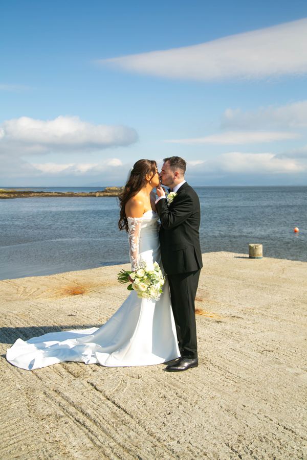Bride and groom embrace on a sandy beach by the sea